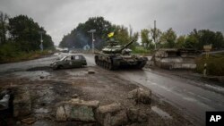 FILE - A Ukrainian tank passes a former Russian checkpoint in the recently retaken area of Izium, Ukraine, Sept. 16, 2022. 