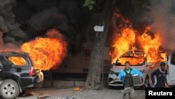 Dos personas corren con bienes saqueados. Detrás, autos en llamas debido a las protestas por el aumento de los precios del combustible y el crimen cuando la inflación alcanzó su nivel más alto en una década, en Puerto Príncipe, Haití, el 14 de septiembre de 2022.
