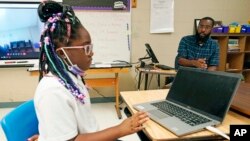 Ryan Johnson, a fifth-grade teacher at Pecan Park Elementary School, right, monitors his daughter Rylei, while she checks her homework schedule before they leave for home in Jackson, Miss., Tuesday, Sept. 6, 2022. (AP Photo/Rogelio V. Solis)