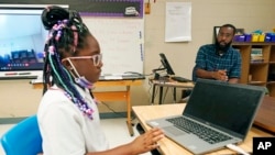 Ryan Johnson, a fifth-grade teacher at Pecan Park Elementary School, right, monitors his daughter Rylei, while she checks her homework schedule before they leave for home in Jackson, Miss., Tuesday, Sept. 6, 2022. (AP Photo/Rogelio V. Solis)