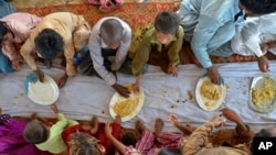 Children eat food provided by a charity group, in Jaffarabad, a flood-hit district of Baluchistan province, Pakistan, Sept. 15, 2022.