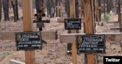 Grave markers listing six-year-old Olesya's name (background) and those of her parents (foreground) are seen at a recently discovered mass burial site in Izium, Kharkiv region, Ukraine. (Twitter/Andriy Yermak)