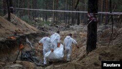 Eksperti iskopavaju tela iz masovne grobnice u gradu Izjum, na severoistoku Ukrajine (Foto: REUTERS/Gleb Garanich)