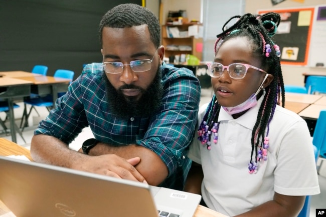 FILE - Ryan Johnson, a fifth-grade teacher at Pecan Park Elementary School, left, checks to see what homework his daughter, Rylei, is bringing home, as they prepare to leave Johnson's classroom in Jackson, Miss., Tuesday, Sept. 6, 2022. (AP Photo/Rogelio V. Solis)