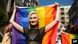 FILE - A woman holds up a rainbow flag as she marches with others during the LGBTQ Pride March in Istanbul, Turkey, June 26, 2022.