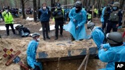 Emergency workers move a body during the exhumation in the recently retaken area of Izium, Ukraine, Sept. 16, 2022. Ukrainian authorities discovered a mass burial site near the recaptured city.
