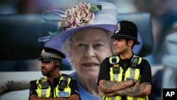 Police officers are backdropped by a photograph of Queen Elizabeth II in London, Sept.16, 2022. The queen will lie in state in Westminster Hall for four full days before her funeral on Sept. 19.