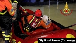 This handout photo from Vigili del Fuoco shows emergency workers rescuing people on a dinghy on a flooded street after heavy rains hit the east coast of Marche region in Senigallia, Italy, Sept. 16, 2022. 