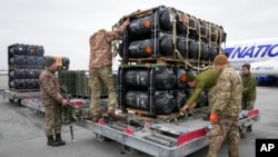 Prajurit Ukraina membongkar rudal anti-tank Javelin, yang dikirimkan sebagai bagian dari paket bantuan keamanan AS ke Ukraina, di bandara Boryspil, di luar Kyiv, Ukraina, 11 Februari 2022. (Foto: Efrem Lukatsky/AP Photo)