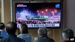 La gente mira una pantalla de televisión que muestra un programa de noticias que informa sobre el desfile militar de Corea del Norte con una imagen en una estación de tren en Seúl, Corea del Sur, el martes 26 de abril de 2022. (Foto AP/Lee Jin-man)