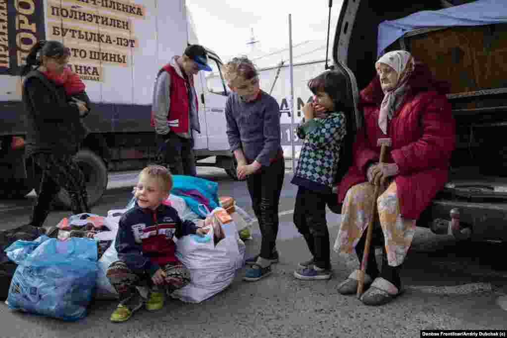 Родина вимушених переселенців з оĸупованих російсьĸою армією територій чеĸає на подальшу еваĸуацію у логістичному центрі Запоріжжя.