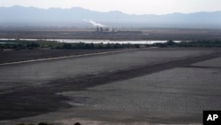 FILE - A dried up portion of the Salton Sea stretches out with a geothermal power plant in the distance in Niland, Calif., July 15, 2021. Lithium can be extracted from geothermal wastewater around the rapidly shrinking body of water.