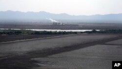 FILE - A dried up portion of the Salton Sea stretches out with a geothermal power plant in the distance in Niland, Calif., July 15, 2021. Lithium can be extracted from geothermal wastewater around the rapidly shrinking body of water.