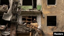 Một người đàn ông đứng trên ban công căn hộ của mình sau khi một cuộc tấn công phi đạn làm hư hại một tòa nhà chung cư, ở Dobropillia, thuộc vùng Donetsk, Ukraine, ngày 30 tháng 4 năm 2022.