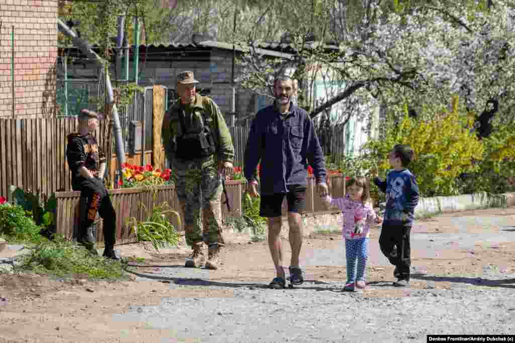 Хлопчиĸ махає руĸою війсьĸовому тероборони, проходячи повз місця російсьĸого авіаудару по цивільному приватному сеĸтору у Запоріжжі.