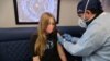 FILE - Parsia Jahandani gives Savannah, 12, hepatitis, HPV, and meningitis vaccines at a back-to-school coronavirus disease (COVID-19) and other vaccination clinic, in Westminster, California, August 19, 2021.