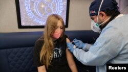 FILE - Parsia Jahandani gives Savannah, 12, hepatitis, HPV, and meningitis vaccines at a back-to-school coronavirus disease (COVID-19) and other vaccination clinic, in Westminster, California, August 19, 2021.