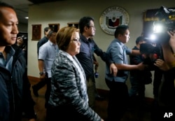 FILE - Philippine Senator Leila de Lima, second from left in foreground, is escorted out of the Philippine Senate premises following a news conference, Feb. 21, 2017, in suburban Pasay city, south of Manila, after the Philippine justice secretary filed charges against her.