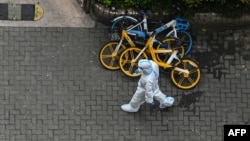 A worker wearing personal protective equipment walks on a street during a COVID-19 coronavirus lockdown in the Jing'an district in Shanghai on April 25, 2022. 