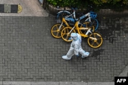 FILE - A worker wearing personal protective equipment walks on a street during a COVID-19 coronavirus lockdown in the Jing'an district in Shanghai on April 25, 2022.