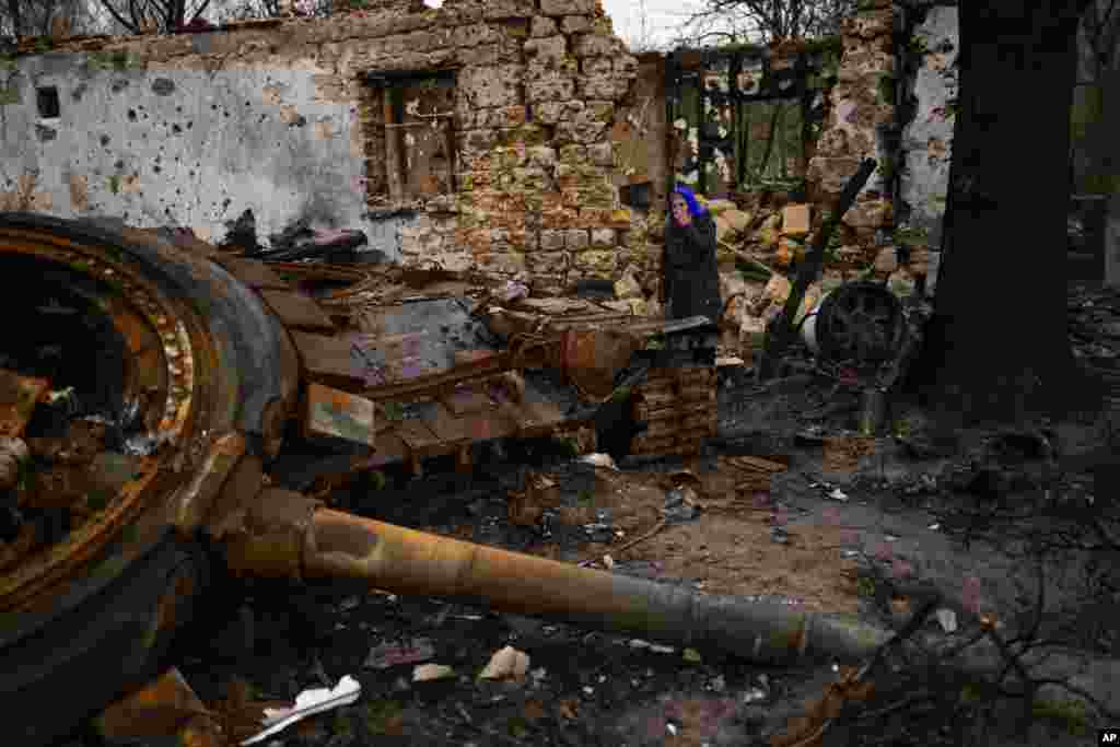 Valentyna Sherba, de 68 años, está junto a un tanque ruso en el patio trasero de la casa de su padre, ambos destruidos, tras una batalla entre tropas rusas y ucranianas el sábado 23 de abril de 2022 en las afueras de Cherníhiv, en el norte de Ucrania. (AP Foto/Francisco Seco)