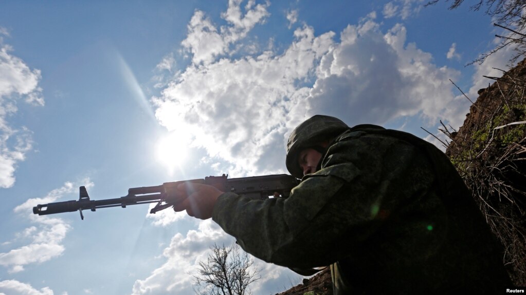 在卢甘斯克与乌军相对峙的分界线附近，一位自称宣布独立的卢甘斯克武装人士持枪瞄准对方阵地。-资料照(photo:VOA)