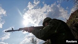 在卢甘斯克与乌军相对峙的分界线附近，一位自称宣布独立的卢甘斯克武装人士持枪瞄准对方阵地。-资料照
