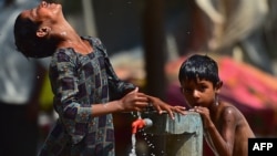 Anak-anak menyegarkan diri di keran pinggir jalan di tengah gelombang panas di Allahabad, India, 28 April 2022. (Foto: AFP)