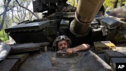 ARCHIVO - Un militar ucraniano de las Fuerzas de Defensa en los amasijos de un tanque utilizado para repeler a las fuerzas ocupantes rusas en el campo de batalla en la región de Donetsk, en el este de Ucrania, en abril de 2022.