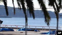 FILE - Bodies of victims covered by sheets at the scene of a truck attack in Nice, southern France, July 15, 2016. 