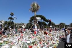 FILE - In this file photo taken on July 18, 2016 People gather near tributes placed at a makeshift memorial near the Promenade des Anglais in Nice for the victims of the Bastille Day attack.