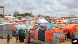 Somali children who fled drought-stricken areas stand by their makeshift shelters in the outskirts of Mogadishu, Sept. 3, 2022. AP