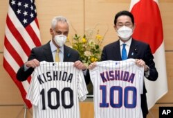 Rahm Emanuel (kiri) Duta Besar AS yang baru untuk Jepang, bersama Perdana Menteri Jepang Fumio Kishida memegang seragam tim bisbol Chicago White Sox dan Chicago Cubs di kediaman resmi perdana menteri di Tokyo, Jepang, Jumat, 4 Februari , 2022. (Franck Robichon/Pool via AP)