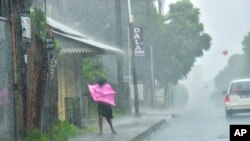 A woman fights gale force winds in the Indian Ocean Island of Mauritius, Feb. 2, 2022. Forecasts say Tropical Cyclone Batsirai is increasing in intensity and is expected to make landfall in central Madagascar on Feb. 5, 2022.