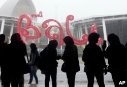 Sejumlah warga berlindung dari hujan setibanya di Bandara Internasional Bali, pada Jumat, 4 Februari 2022. (Foto: AP)