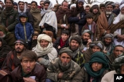 FILE - Hundreds of Afghan men gather to apply for humanitarian aid, in Qala-e-Naw, Afghanistan, Dec. 14, 2021.