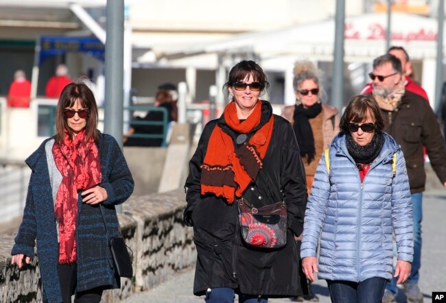 People not wearing face masks walk in Saint-Jean-de-Luz southwestern France, Wednesday, Fev.2, 2022. England, France, Ireland, the Netherlands and several Nordic countries have taken steps to end or loosen their restrictions. (AP Photo/Bob Edme)