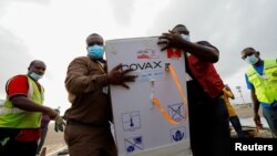 FILE - Workers carry boxes of COVID-19 vaccines, at the Kotoka International Airport in Accra, Ghana, May 7, 2021.