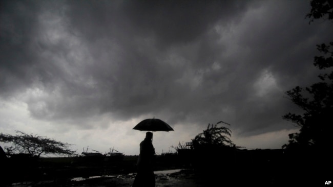FILE - A villager under dark clouds in Balasore area in Odisha, India on May 25, 2021, ahead of a powerful storm heading toward the eastern coast. (AP Photo/File)