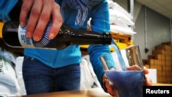 Hoppy Urban Brew (HUB) worker Mathilde Vanmansart pours a bottle of the Line blue beer, made with spirulina algae, into a glass during inside the brewery near Lille, France, January 31, 2022. REUTERS/Ardee Napolitano