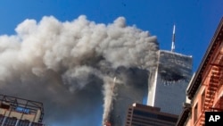 FILE - Smoke rises from the burning twin towers of the World Trade Center after hijacked planes crashed into them, in New York City, Sept. 11, 2001