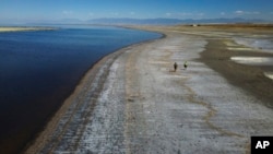 Dos personas caminan el 6 de septiembre de 2022 por la ribera del Gran Lago Salado, en Utah, EEUU, donde el nivel del agua ha descendido a mínimos históricos. 