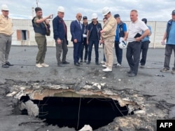 This handout photo taken on Sept. 1, 2022, and obtained from the International Atomic Energy Agency on Sept. 7, 2022, shows IAEA team members inspecting damage caused by shelling on the roof of a building at the Zaporizhzhia nuclear power plant, in Enerhodar, Zaporizhzhia region, Ukraine.