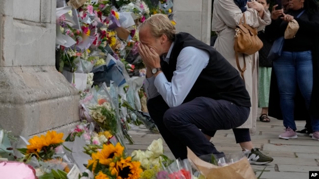 Un doliente está abrumado por la emoción mientras presenta sus respetos a las puertas del Palacio de Buckingham en Londres, el viernes 9 de septiembre de 2022.