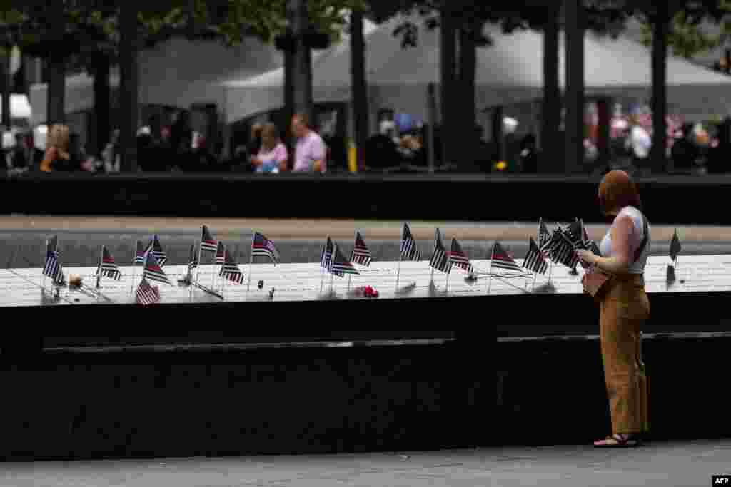 A relative of a victim places U.S. flags on the 9/11 Memorial in New York City, Sept. 11, 2022