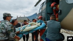 In this photo released by Xinhua News Agency, rescuers using helicopter to transfer injured villagers following an earthquake in Detuo Town of Luding County, southwest China's Sichuan Province, Sept. 6, 2022.