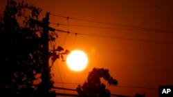 FILE - Sunrise is viewed between power lines in Sacramento, Calif., Sept. 8, 2022. 