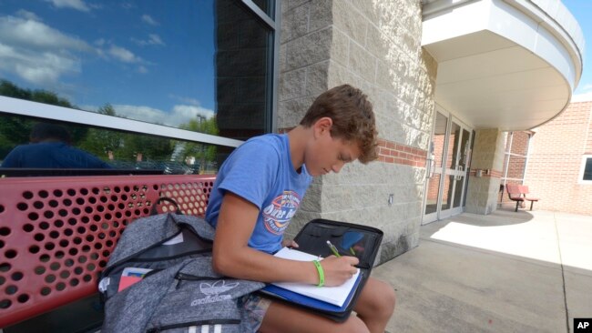 Braylon Price, 13, writes a note before heading home from Bellefonte Middle School Wednesday, Aug. 31, 2022, in Bellefonte, Pa. (AP Photo/Gary M. Baranec)
