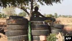 FILE - A Togolese soldier holding a machine gun keeps watch under a tree surrounded by tires in Yemboate, northern Togo, Feb. 17, 2020. Togolese security agencies have intensified surveillance around border with neighboring Burkina Faso to prevent insurgents from crossing over.,
