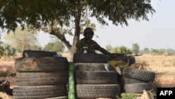 FILE - A Togolese soldier holding a machine gun keeps watch under a tree surrounded by tires in Yemboate, northern Togo. Taken Feb. 17, 2020. 